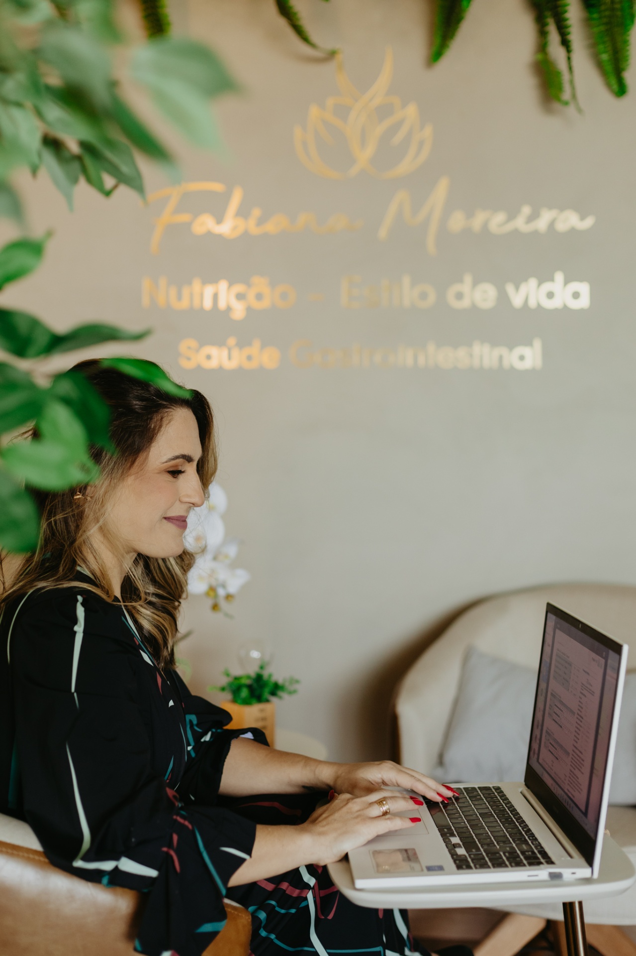 Fabiana Moreira em atendimento online, com o notebook no consultório acolhedor